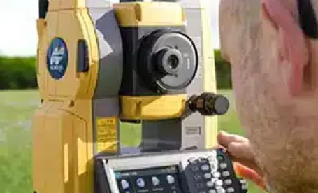 An individual looking through Topcon's OS 200 Total Station.